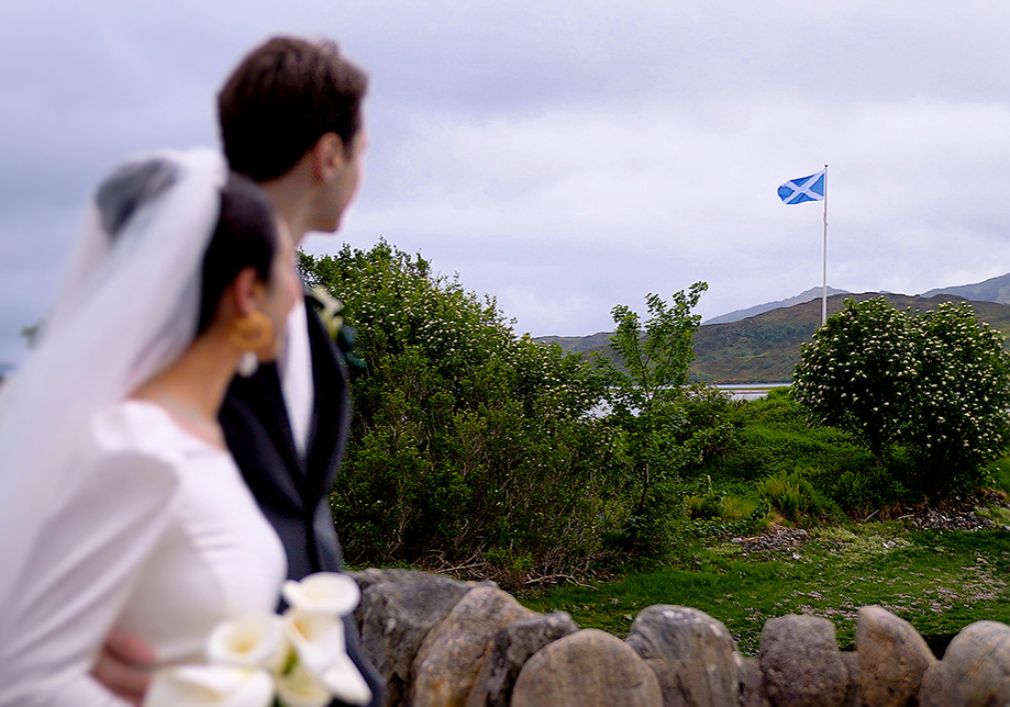 Bride and groom look at Scottish flag flying